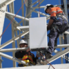Trabajadores de telecomunicaciones instalan una antena 5G en una torre celular.