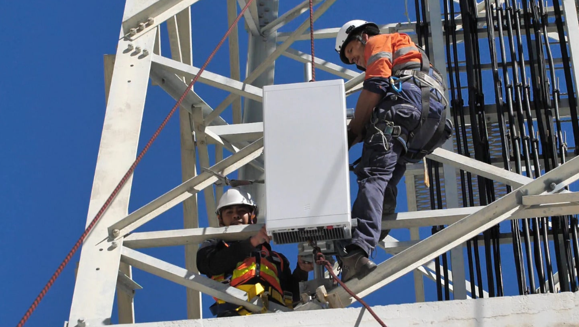 Trabajadores de telecomunicaciones instalan una antena 5G en una torre celular.